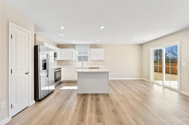 kitchen featuring light countertops, appliances with stainless steel finishes, white cabinets, a sink, and light wood-type flooring