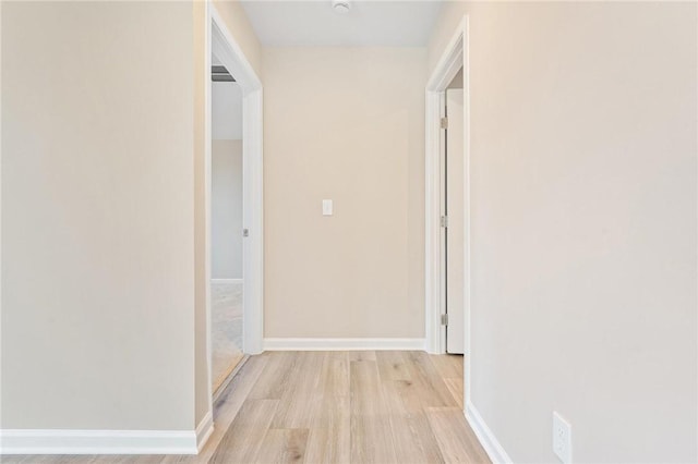 hall with baseboards and light wood finished floors