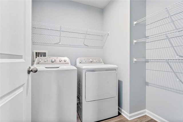 clothes washing area featuring laundry area, independent washer and dryer, baseboards, and wood finished floors