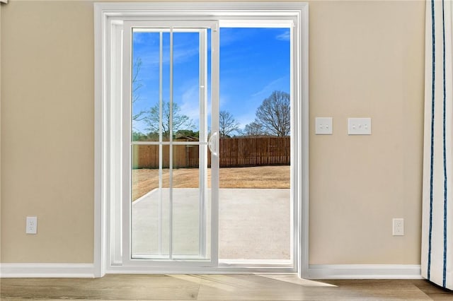 doorway to outside featuring baseboards and wood finished floors