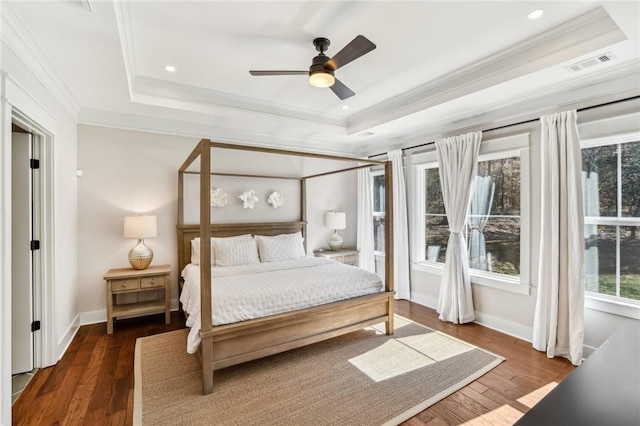 bedroom featuring a raised ceiling, visible vents, dark wood-type flooring, ornamental molding, and baseboards