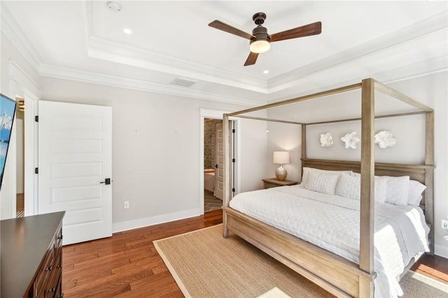 bedroom featuring baseboards, crown molding, a tray ceiling, and wood finished floors