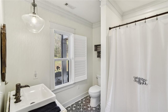 bathroom featuring visible vents, toilet, ornamental molding, a sink, and baseboards