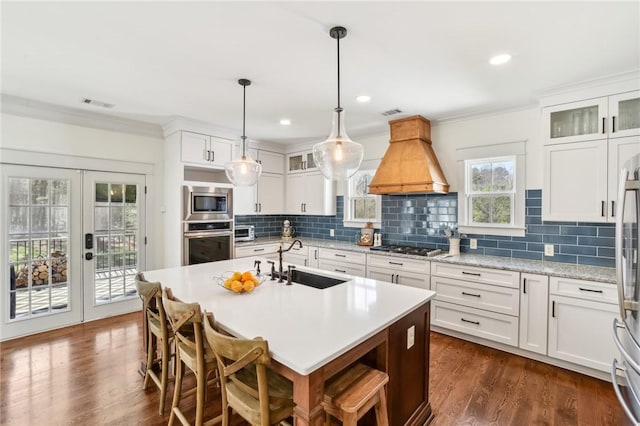 kitchen with stainless steel appliances, premium range hood, a sink, french doors, and dark wood finished floors