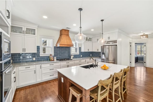 kitchen with appliances with stainless steel finishes, white cabinetry, a sink, and custom exhaust hood