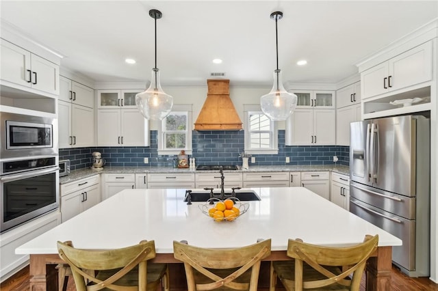 kitchen with stainless steel appliances, light countertops, custom range hood, and a sink