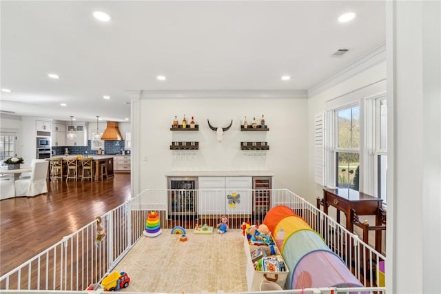 playroom featuring recessed lighting, wood finished floors, visible vents, a bar, and crown molding