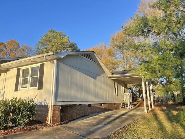 view of home's exterior featuring crawl space, an attached carport, and concrete driveway