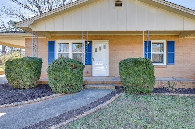 view of front of home featuring covered porch, brick siding, and board and batten siding