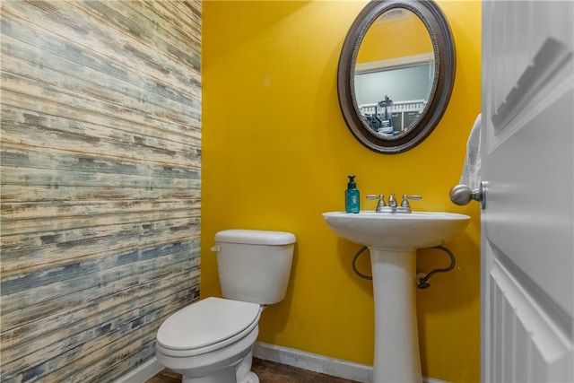 half bath featuring baseboards and toilet