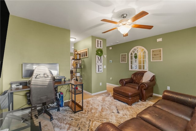 office space with a ceiling fan and baseboards