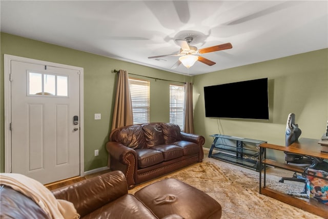 living area with a ceiling fan, visible vents, and baseboards