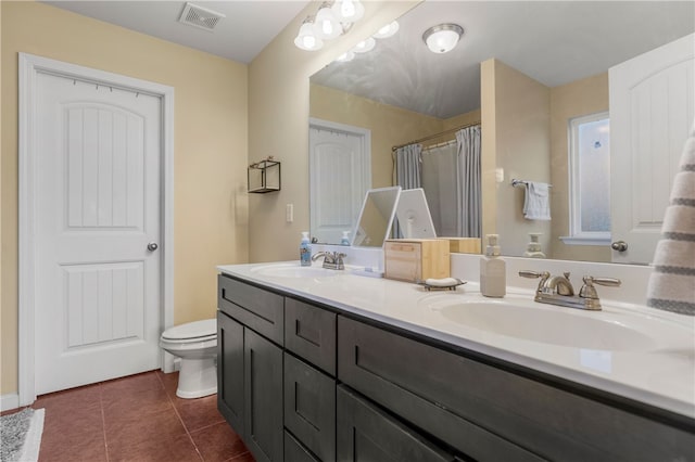 bathroom featuring toilet, visible vents, a sink, and tile patterned floors