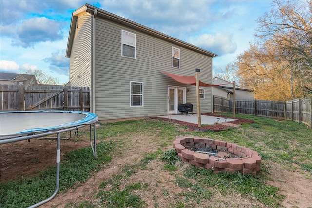 back of house with a trampoline, french doors, a patio, a lawn, and a fenced backyard