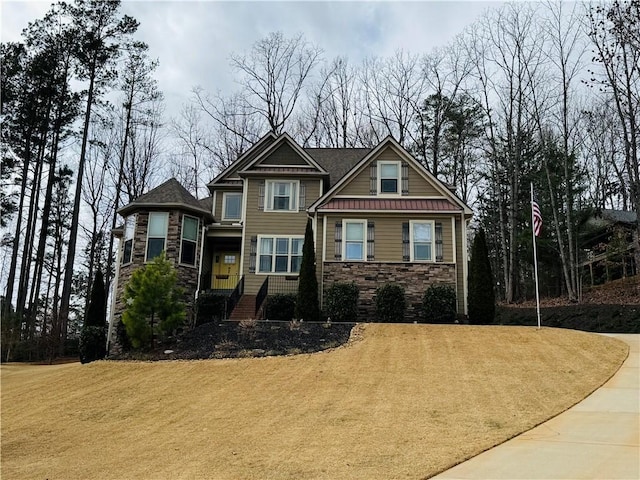 craftsman house featuring stone siding and a front lawn