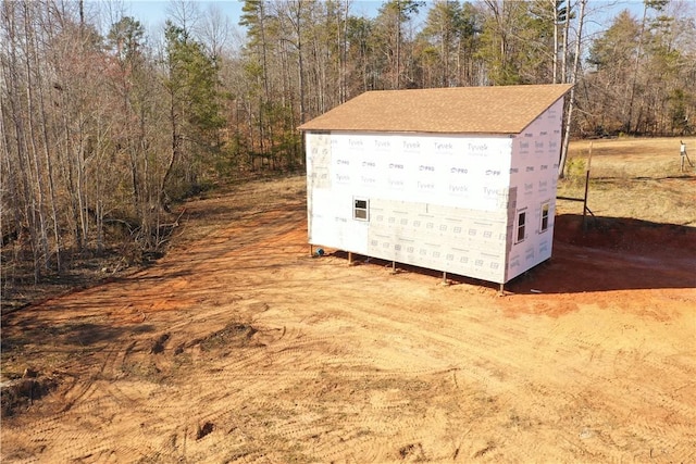 view of outdoor structure with a wooded view and an outbuilding