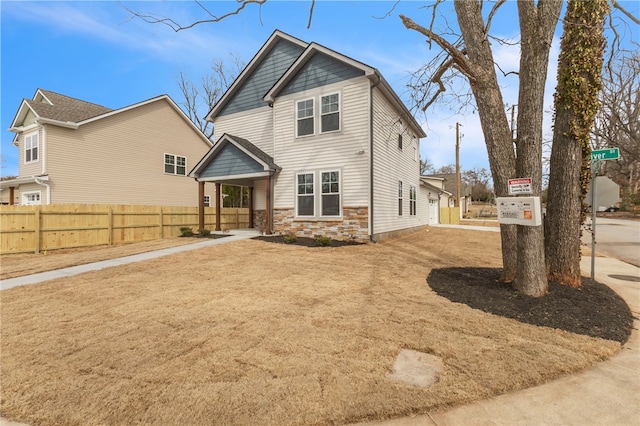 back of house featuring stone siding and fence