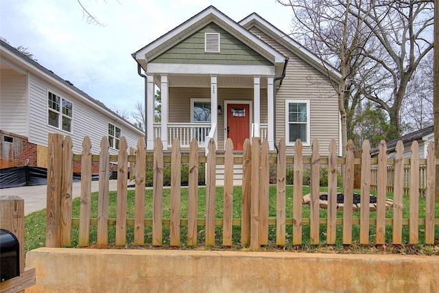 shotgun-style home featuring a porch and a fenced front yard