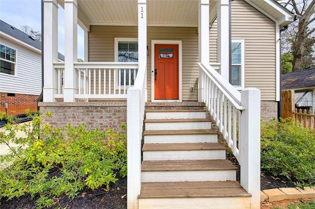 doorway to property with a porch and brick siding