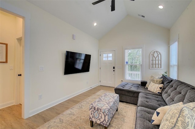 living area with visible vents, light wood-style flooring, ceiling fan, high vaulted ceiling, and baseboards