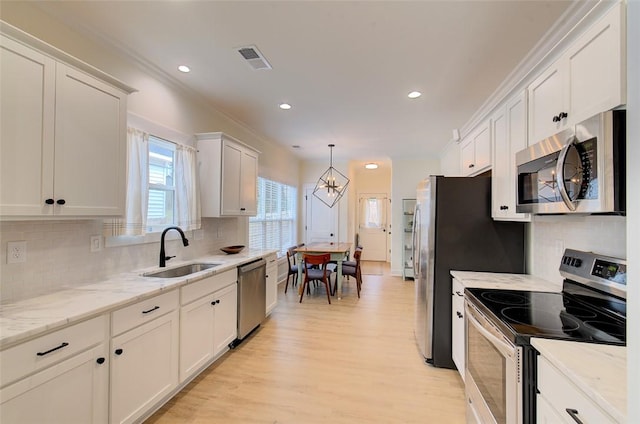 kitchen with visible vents, appliances with stainless steel finishes, light wood-style floors, white cabinetry, and a sink