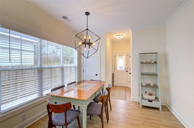 dining area featuring visible vents, baseboards, light wood-style flooring, an inviting chandelier, and crown molding