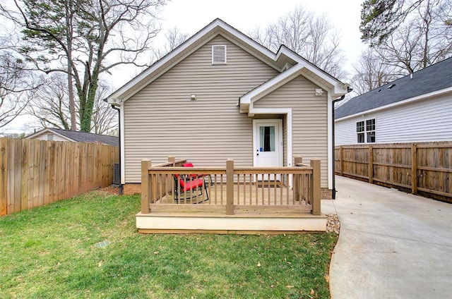 rear view of property featuring a fenced backyard, a yard, and a wooden deck