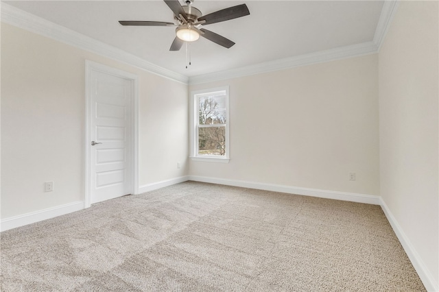 carpeted spare room with ornamental molding, a ceiling fan, and baseboards