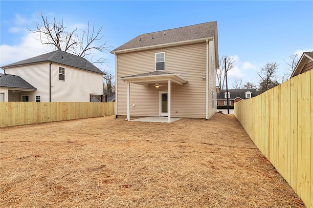 back of property with a fenced backyard and a patio