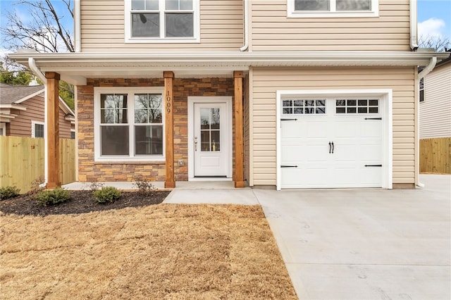 exterior space featuring a garage, stone siding, fence, and concrete driveway