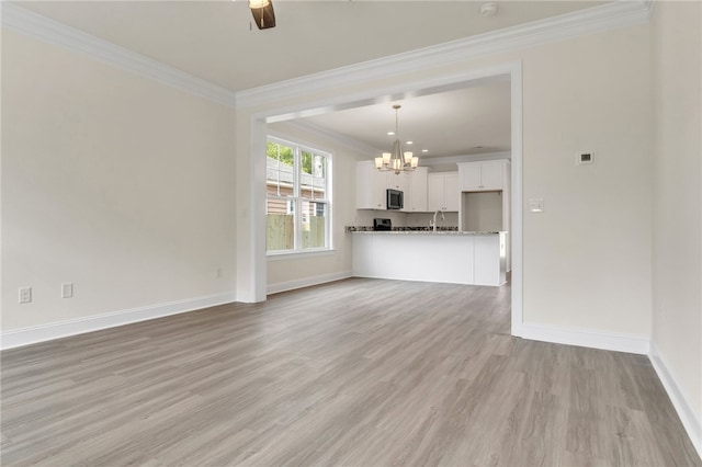 unfurnished living room featuring baseboards, crown molding, light wood-style floors, a sink, and ceiling fan with notable chandelier