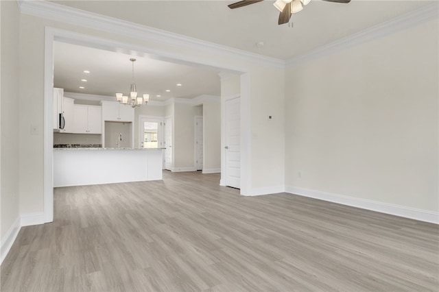 unfurnished living room with ornamental molding, light wood finished floors, ceiling fan with notable chandelier, and baseboards