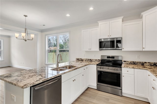 kitchen featuring appliances with stainless steel finishes, a peninsula, crown molding, white cabinetry, and a sink