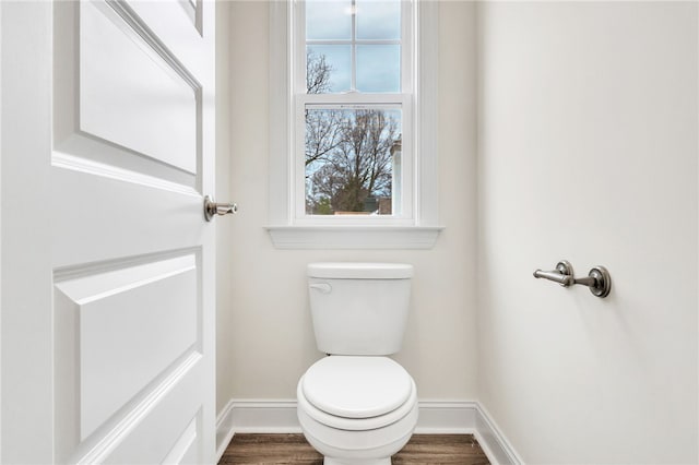 bathroom with toilet, baseboards, and wood finished floors