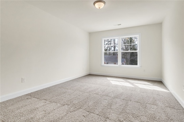 carpeted spare room with visible vents and baseboards