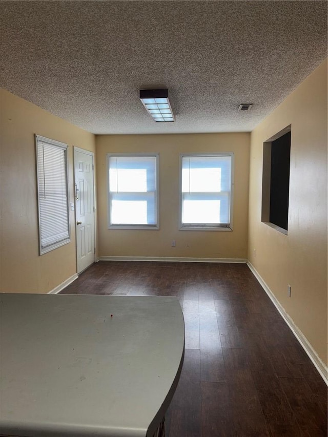 interior space featuring baseboards, visible vents, a textured ceiling, and hardwood / wood-style floors