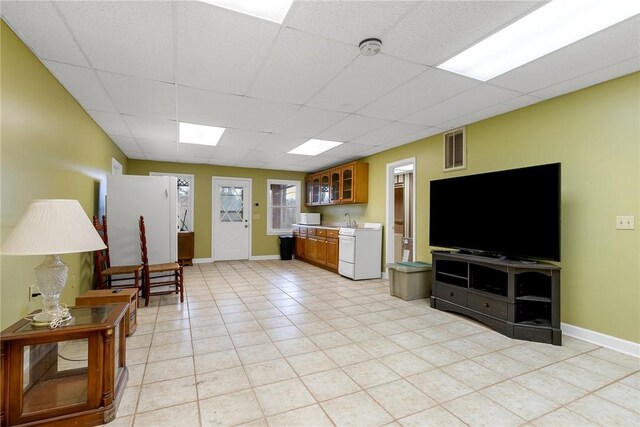 unfurnished living room with a paneled ceiling, visible vents, baseboards, and light tile patterned floors