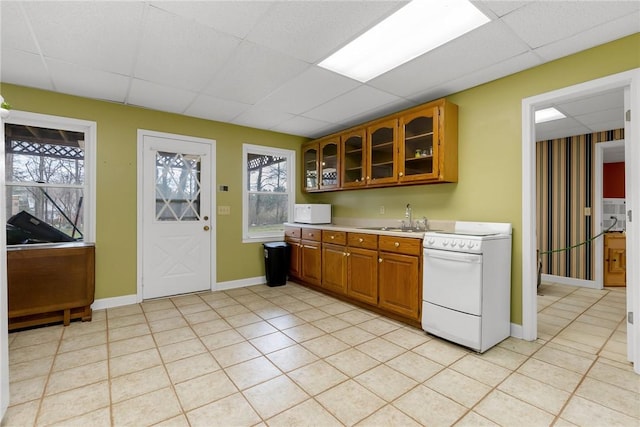 kitchen featuring a paneled ceiling, light countertops, a sink, and stove