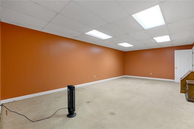 spare room with a paneled ceiling, baseboards, and light colored carpet