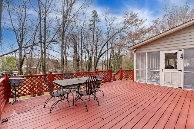 wooden deck featuring outdoor dining area and a sunroom