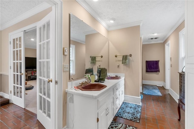 bathroom with brick floor, french doors, a sink, and ornamental molding