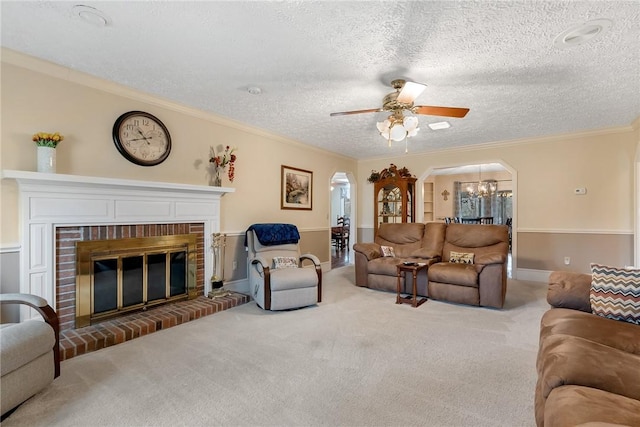 living area with arched walkways, a textured ceiling, carpet flooring, ornamental molding, and a brick fireplace