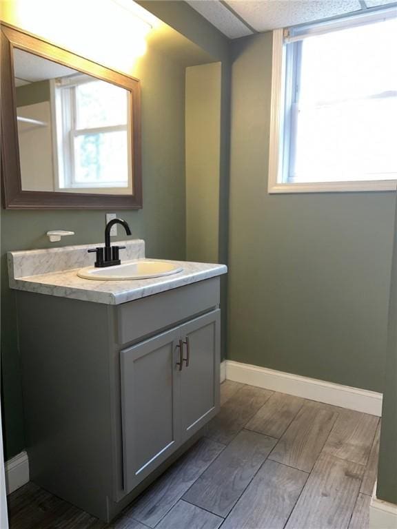 bathroom featuring wood finish floors, vanity, and baseboards