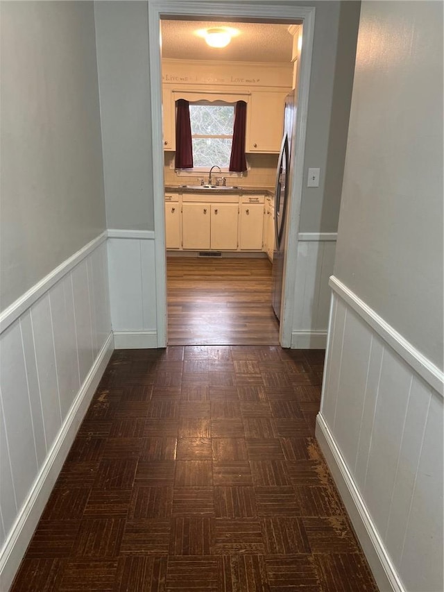 corridor with a wainscoted wall and a sink