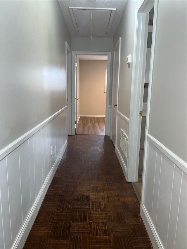 hallway featuring a wainscoted wall and attic access