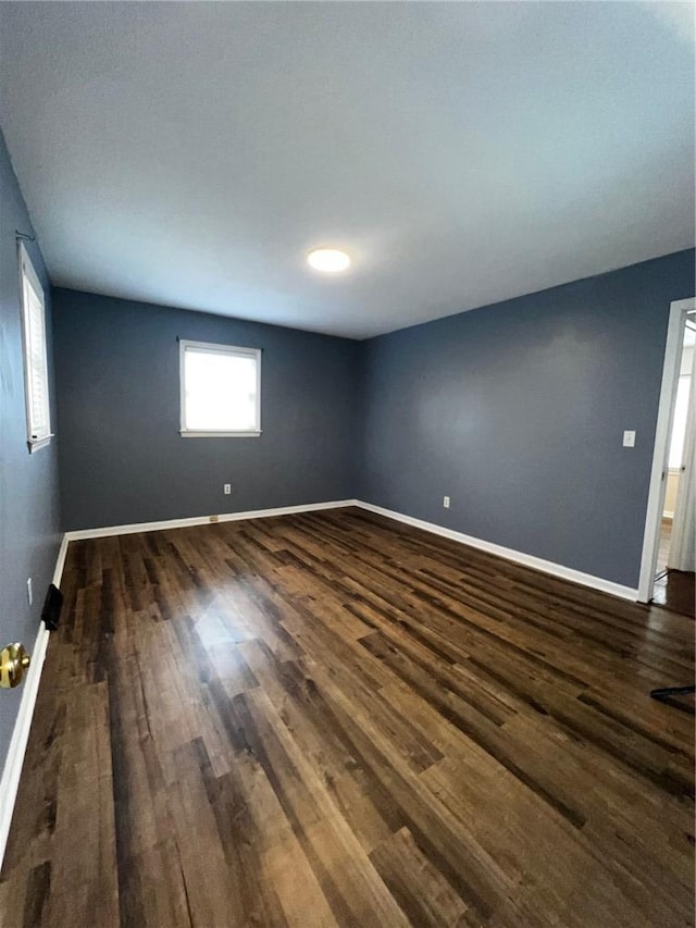 unfurnished room with dark wood-type flooring and baseboards