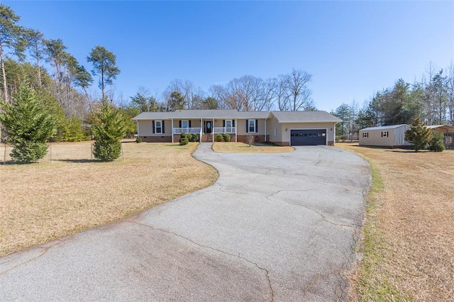 ranch-style home with a porch, a front yard, driveway, and an attached garage