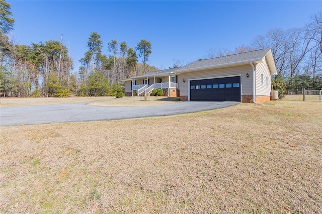 ranch-style home with a porch, fence, a garage, driveway, and a front lawn