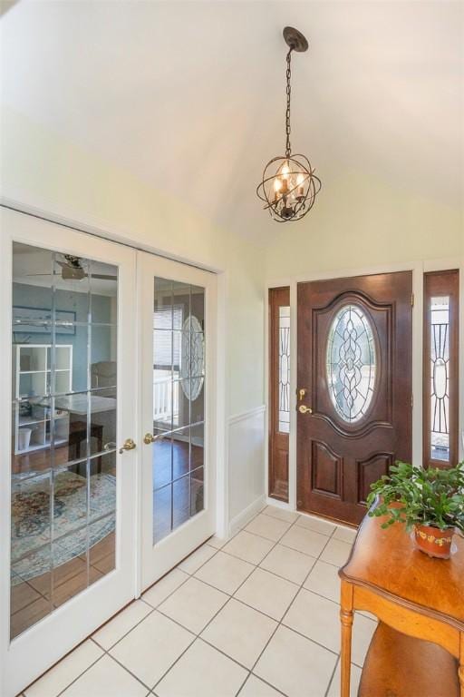 entryway featuring french doors, a notable chandelier, vaulted ceiling, and light tile patterned floors