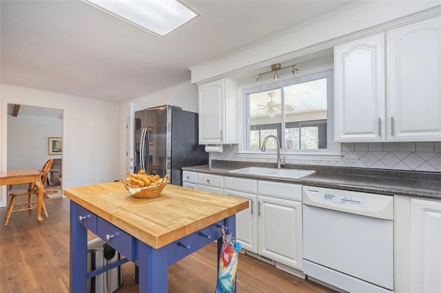 kitchen with white cabinets, white dishwasher, wood counters, a sink, and stainless steel fridge